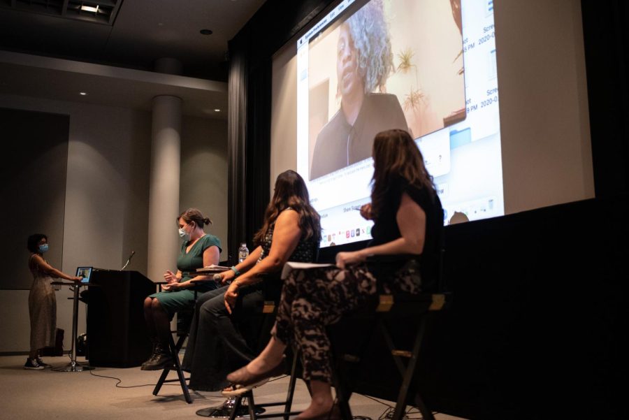 Three women sit on a stage.