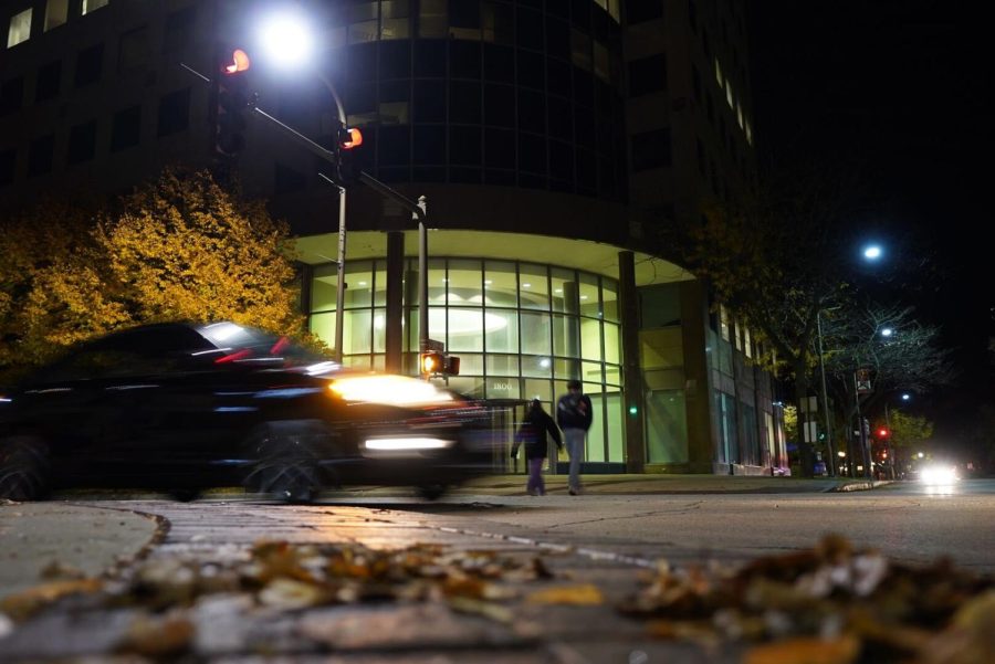 Glass building at night with car blurred in front.